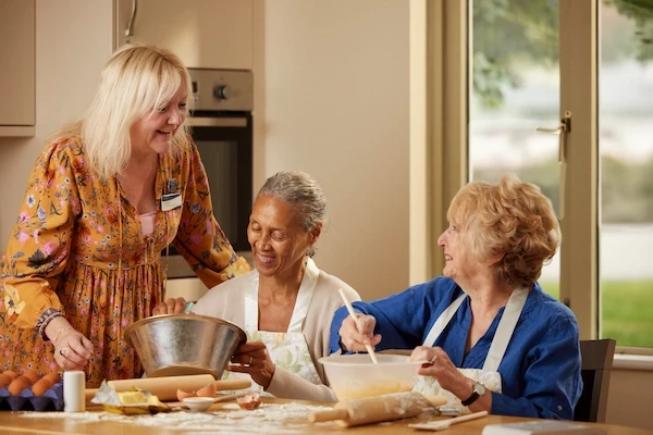 A carer and two residents baking in the kitchen