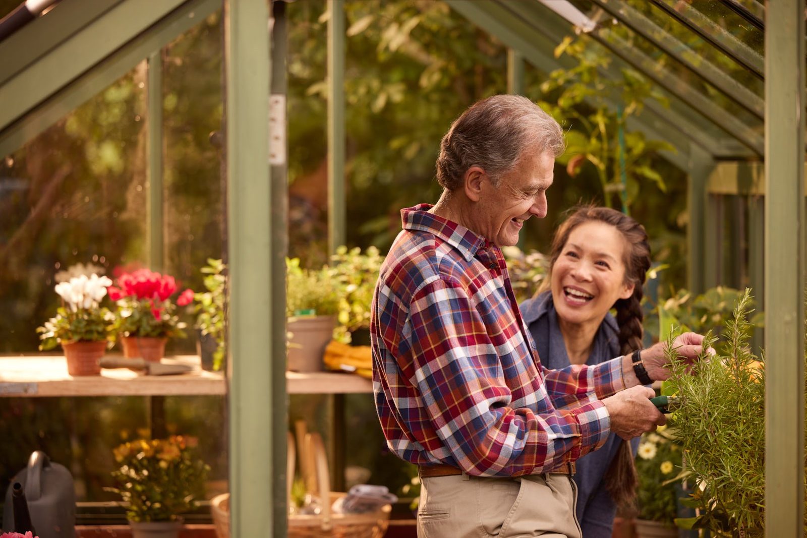 Bluebird Care: a carer and a client laughing in a greenhouse