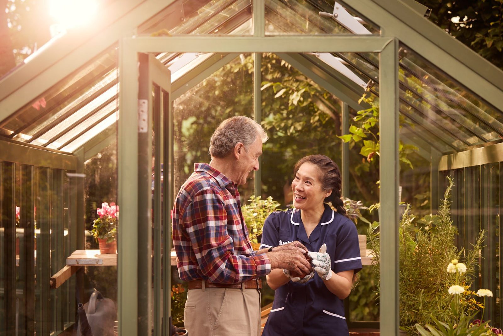 Bluebird Care: a carer and a client talking in a greenhouse