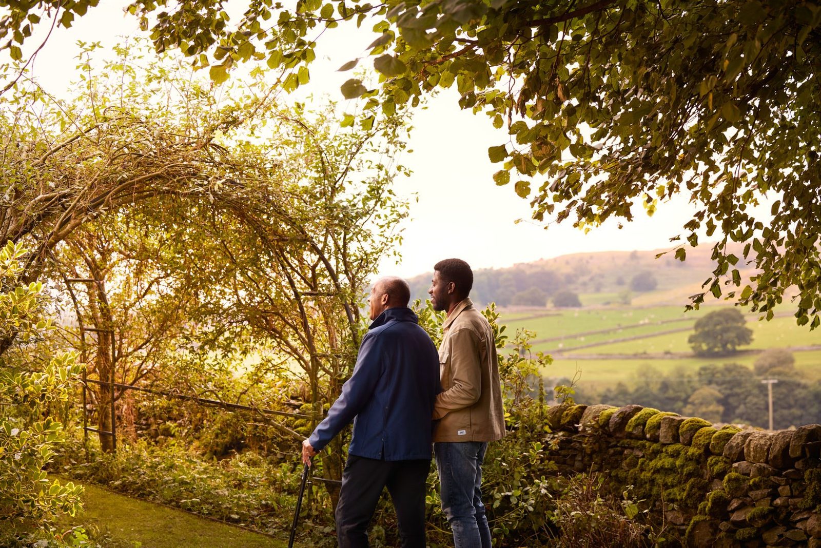 Bluebird Care: a carer and a client walking through a garden in the evening light