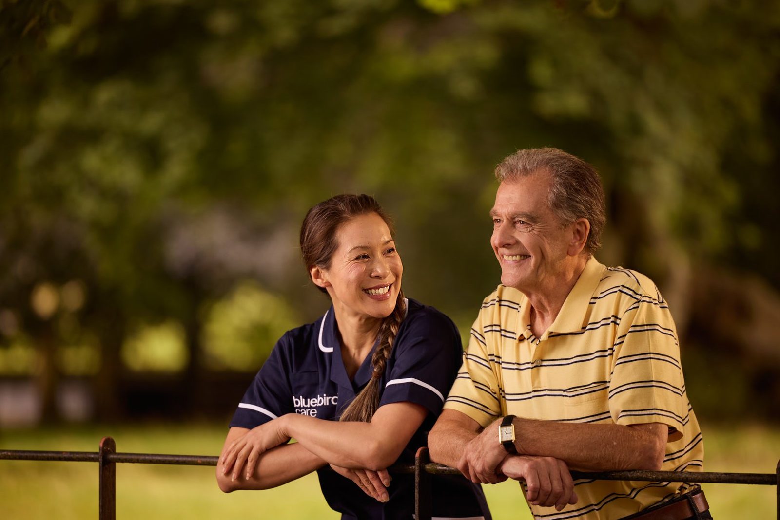 Bluebird Care: a carer and a client smiling on a garden fence