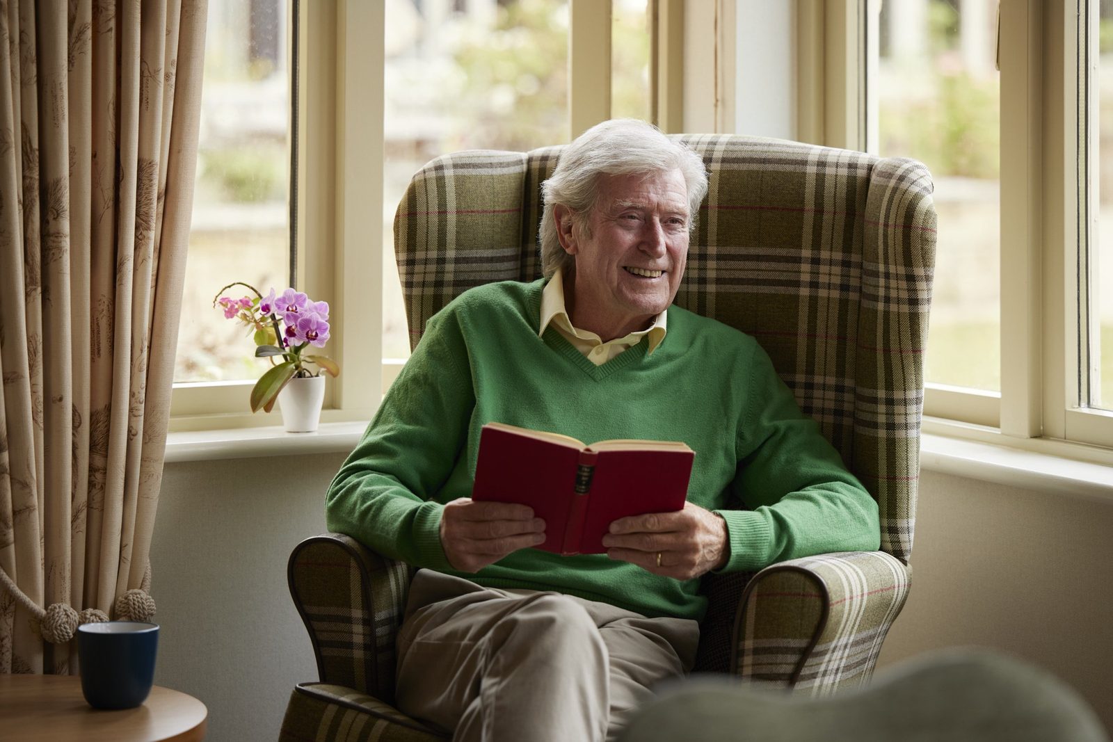 Elizabeth Finn Homes: a resident reading in an armchair by the window