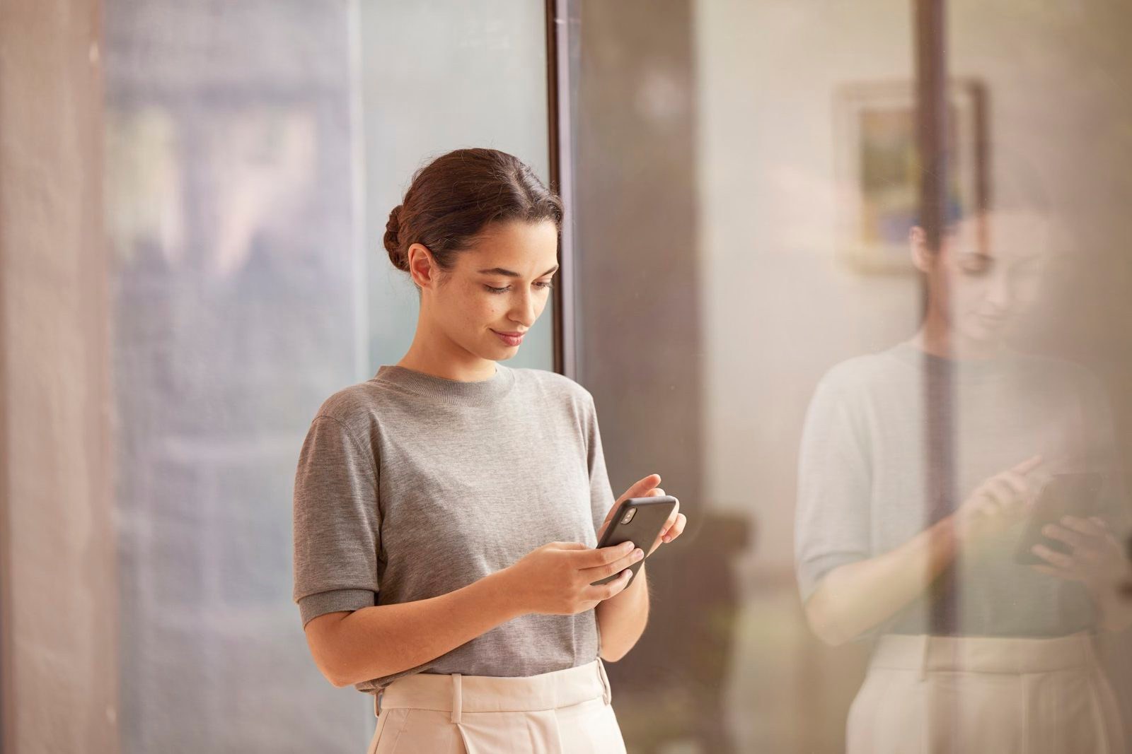 Florence: a woman checking her phone beside a glass wall