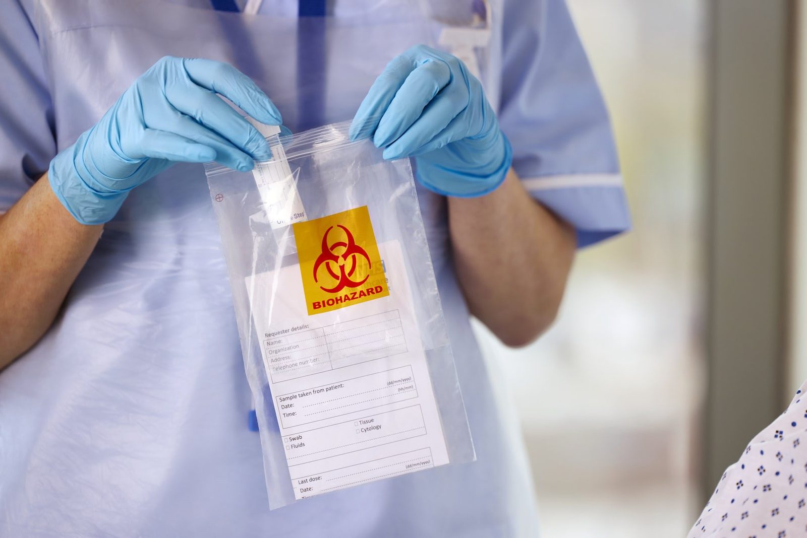 Gloved hands sealing a biohazard specimen bag