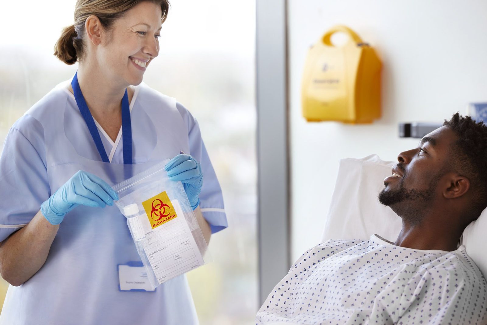 A smiling nurse holding a biohazard specimen bag beside a laughing patient